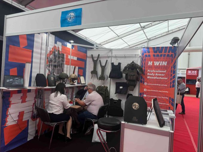 H Win's booth at a trade show, showcasing their range of ballistic protection products, including body armor and helmets