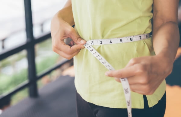 Person measuring waist with tape measure for accurate body armor sizing